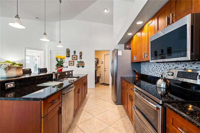 kitchen with light tile patterned floors, stainless steel appliances, a sink, brown cabinets, and decorative backsplash