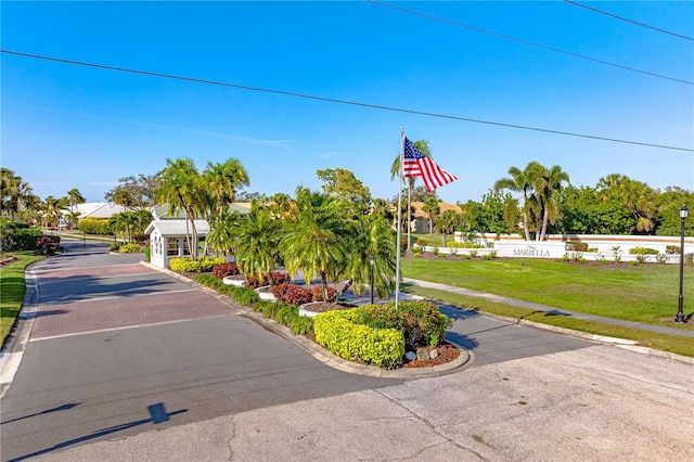 view of street featuring street lights, curbs, a gated entry, and sidewalks