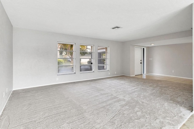 carpeted spare room featuring baseboards and visible vents