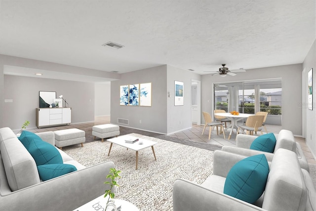 living area with ceiling fan, baseboards, visible vents, and a textured ceiling