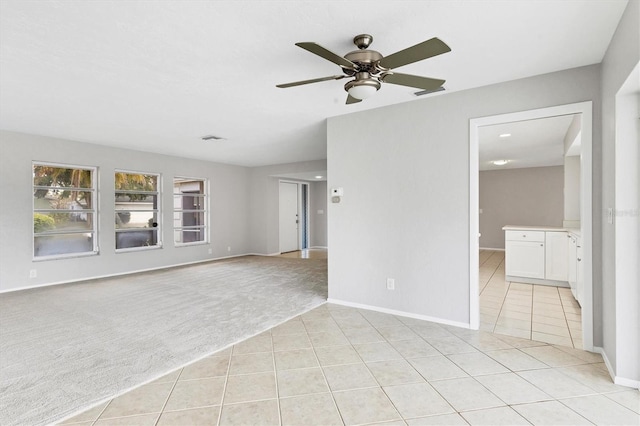 interior space with visible vents, baseboards, light colored carpet, light tile patterned flooring, and a ceiling fan