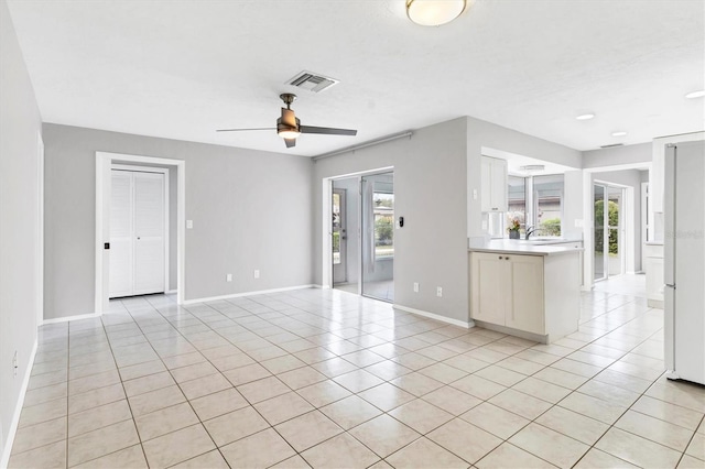 unfurnished living room featuring light tile patterned flooring, visible vents, baseboards, and a ceiling fan