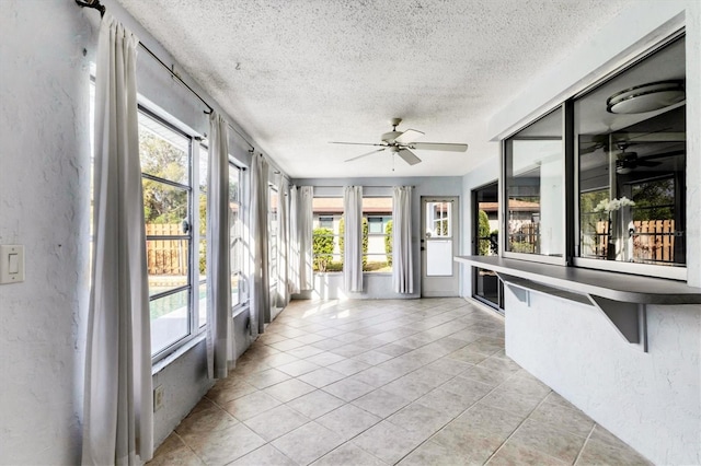 unfurnished sunroom featuring ceiling fan