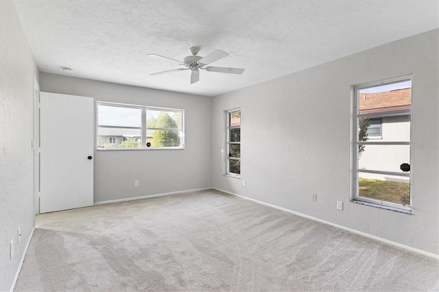 spare room featuring a textured wall, baseboards, carpet, and a textured ceiling