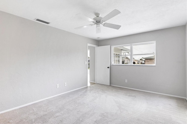 unfurnished room featuring baseboards, carpet, visible vents, and ceiling fan