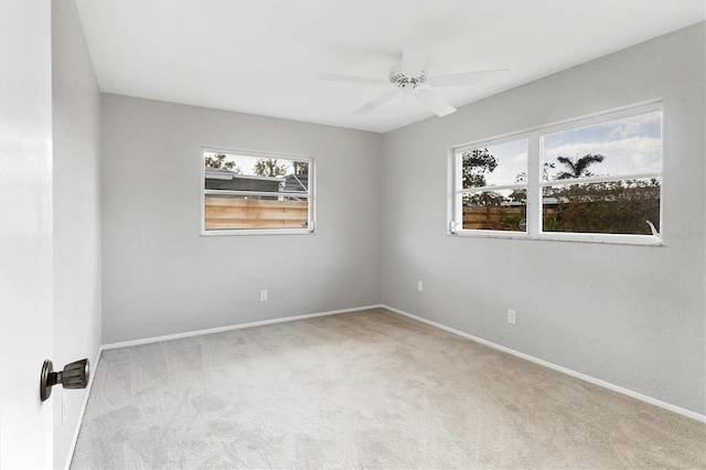 carpeted spare room featuring a ceiling fan and baseboards