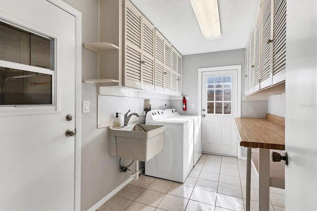 washroom with baseboards, light tile patterned floors, separate washer and dryer, cabinet space, and a sink