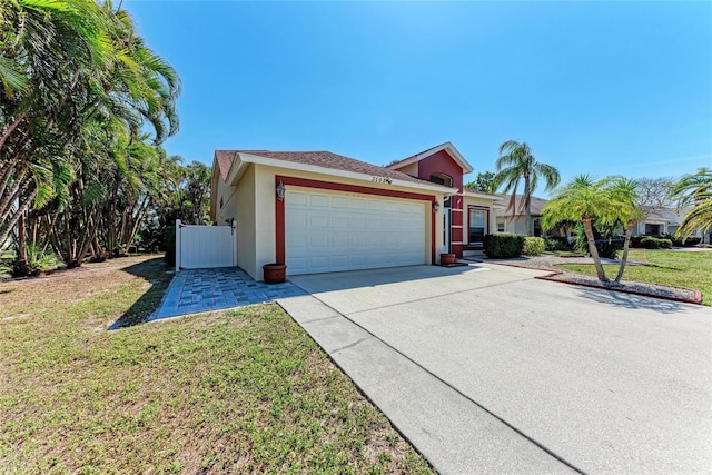 single story home with a garage, driveway, a front lawn, and stucco siding