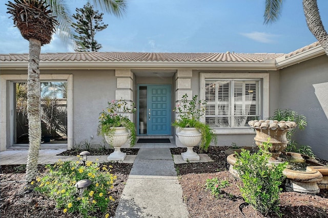 view of exterior entry featuring a tile roof and stucco siding