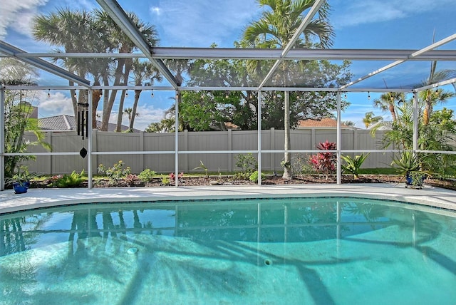 view of pool featuring glass enclosure, a fenced backyard, and a fenced in pool