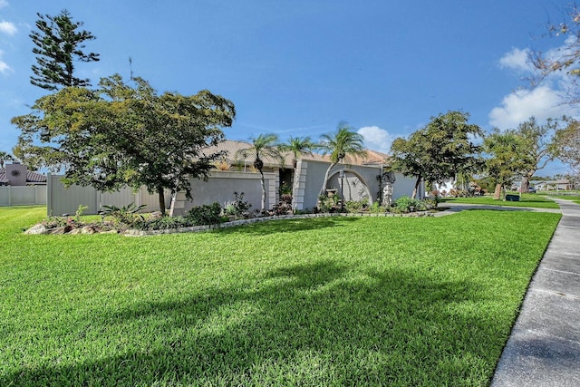 view of front facade featuring fence, a front lawn, and stucco siding