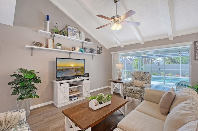 living area featuring baseboards, a ceiling fan, light wood-style flooring, vaulted ceiling with beams, and a textured ceiling