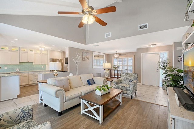 living area with light wood-style floors, visible vents, and high vaulted ceiling