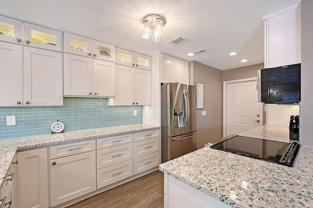 kitchen with light wood finished floors, tasteful backsplash, visible vents, black appliances, and white cabinetry