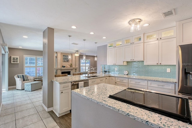 kitchen featuring stainless steel fridge, tasteful backsplash, a peninsula, black electric cooktop, and a sink