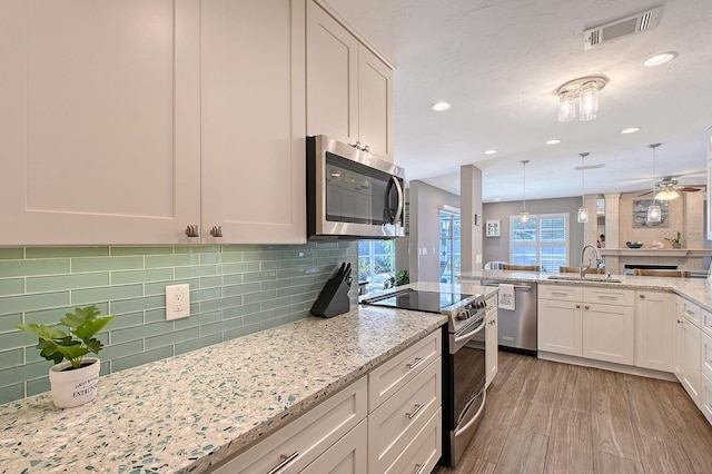 kitchen with visible vents, decorative backsplash, appliances with stainless steel finishes, a sink, and light wood-type flooring