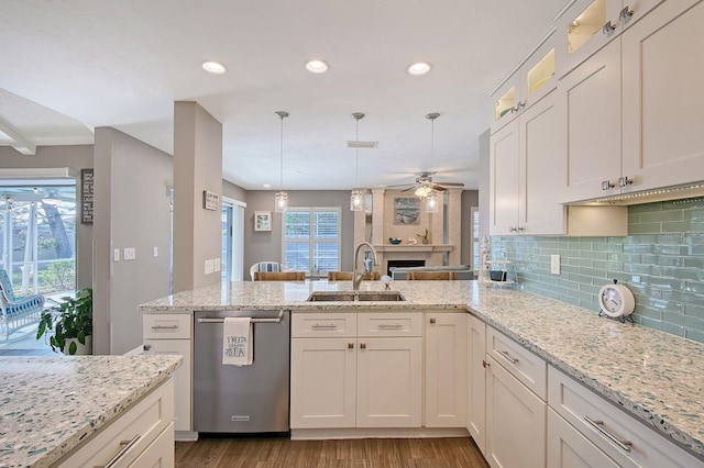 kitchen featuring dark wood finished floors, a ceiling fan, a peninsula, stainless steel dishwasher, and a sink