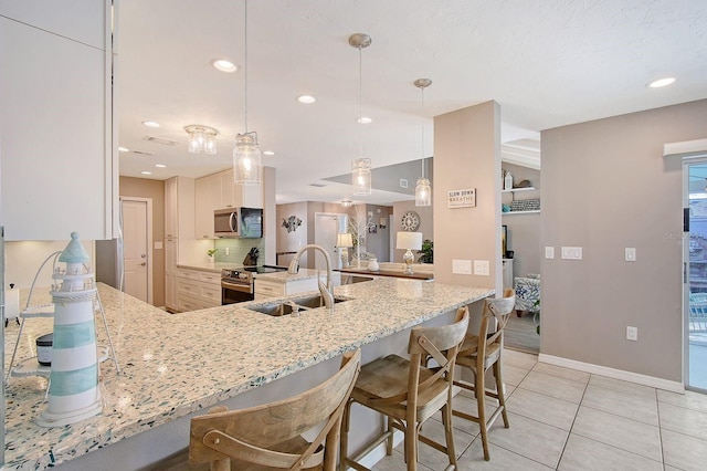 kitchen featuring a peninsula, a breakfast bar area, stainless steel appliances, and a sink