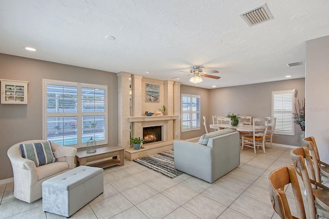 living room featuring a high end fireplace, visible vents, and a healthy amount of sunlight