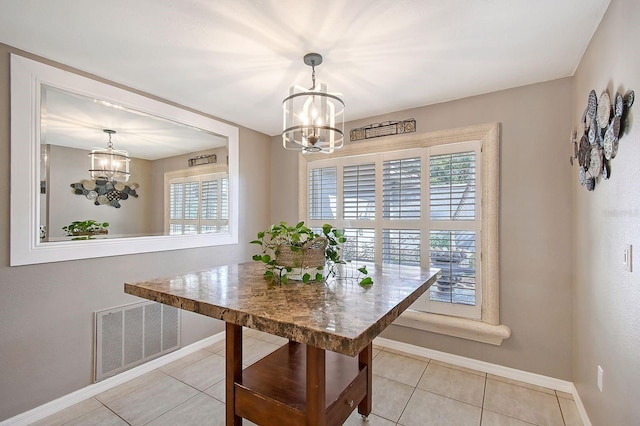 tiled dining space featuring baseboards, a healthy amount of sunlight, visible vents, and an inviting chandelier