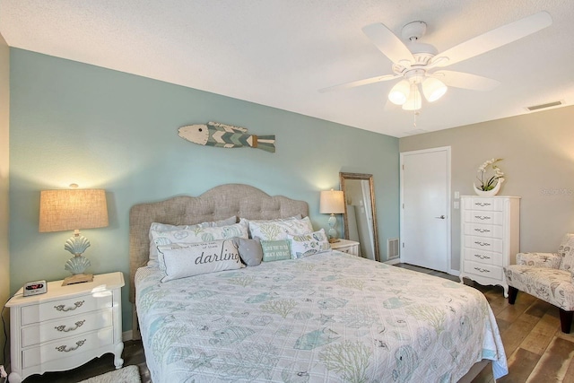 bedroom with a ceiling fan, baseboards, visible vents, and wood finished floors