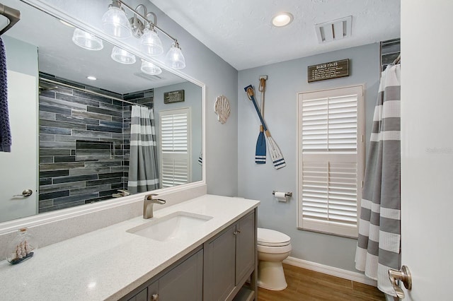 bathroom featuring visible vents, toilet, vanity, wood finished floors, and baseboards