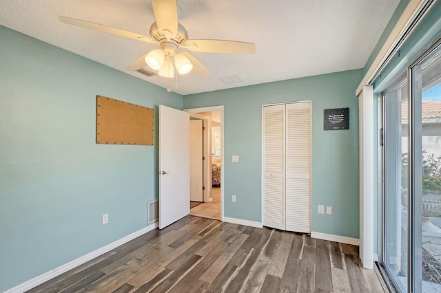 unfurnished bedroom with dark wood-type flooring, a closet, visible vents, and baseboards