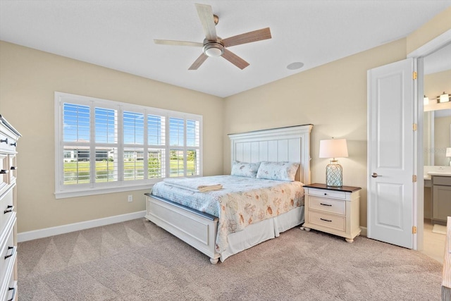 bedroom with light carpet, ceiling fan, baseboards, and connected bathroom