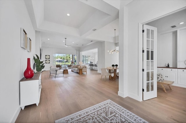 hallway with visible vents, wood finished floors, a tray ceiling, a chandelier, and recessed lighting