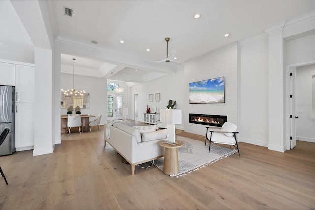 living area with a large fireplace, light wood-style flooring, visible vents, and a notable chandelier