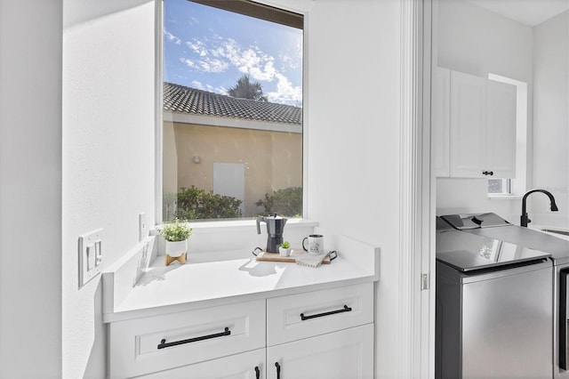 clothes washing area featuring washing machine and dryer, cabinet space, and plenty of natural light