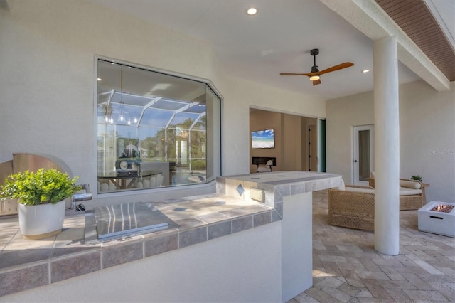 view of patio with exterior kitchen, an outdoor fire pit, and a ceiling fan