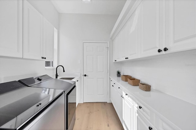 laundry area with washer and dryer, cabinet space, and light wood-style flooring