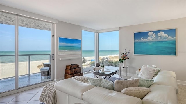 living room featuring a water view, baseboards, a beach view, and light tile patterned flooring