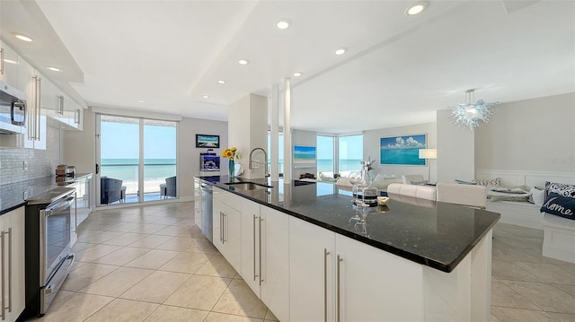 kitchen featuring a sink, open floor plan, white cabinets, appliances with stainless steel finishes, and light tile patterned flooring