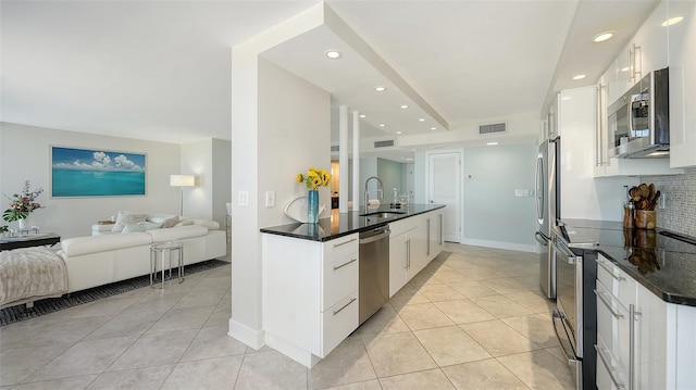 kitchen with a sink, light tile patterned flooring, visible vents, open floor plan, and appliances with stainless steel finishes