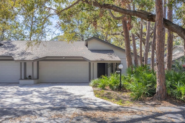 view of front of property with a garage, a shingled roof, decorative driveway, and stucco siding