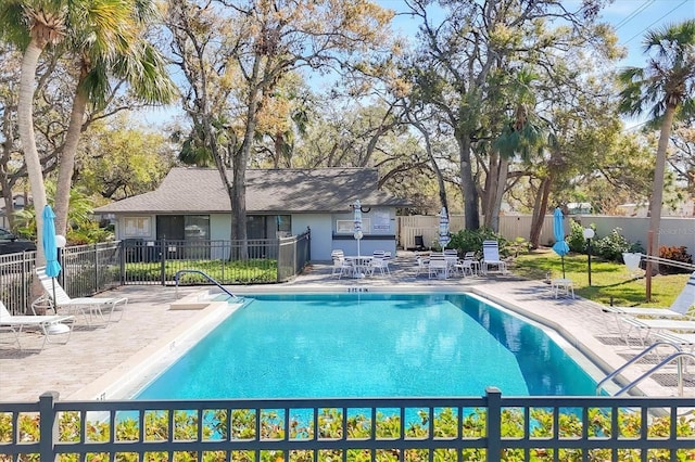 community pool with a patio area and fence