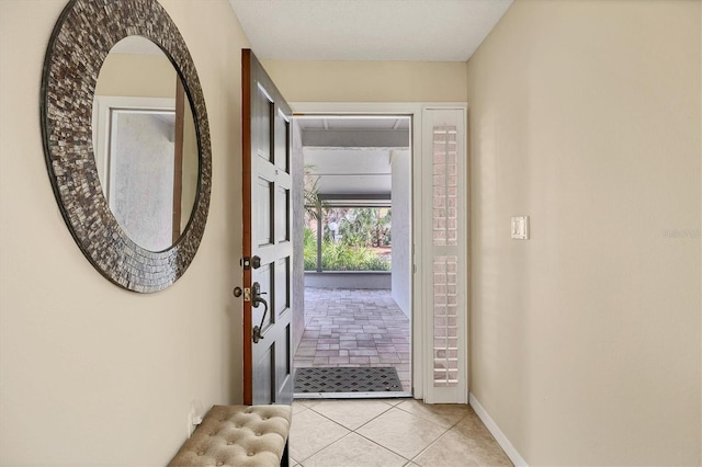 doorway with light tile patterned floors and baseboards