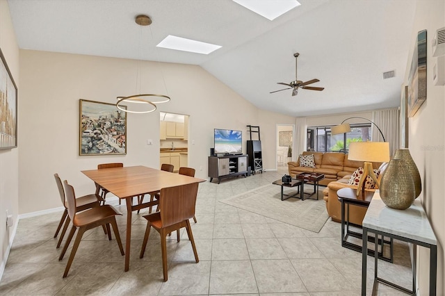 dining area featuring light tile patterned floors, ceiling fan, visible vents, baseboards, and lofted ceiling with skylight