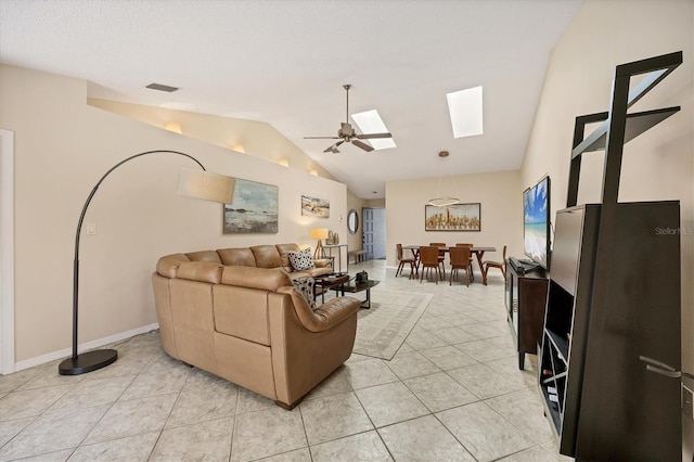 living room with light tile patterned floors, visible vents, lofted ceiling with skylight, a ceiling fan, and baseboards