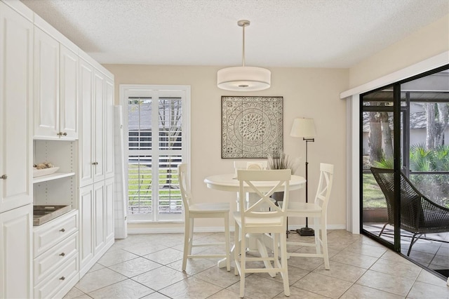 dining area featuring a textured ceiling, baseboards, and light tile patterned floors