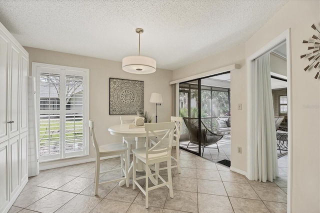 dining space featuring a textured ceiling, light tile patterned flooring, and baseboards