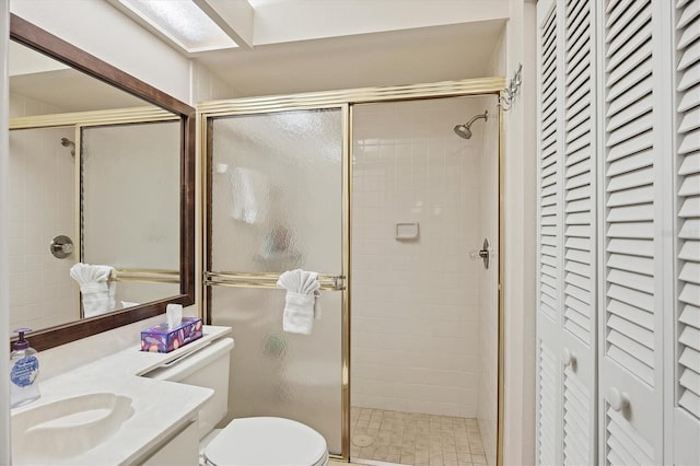 bathroom with toilet, a stall shower, a closet, and vanity