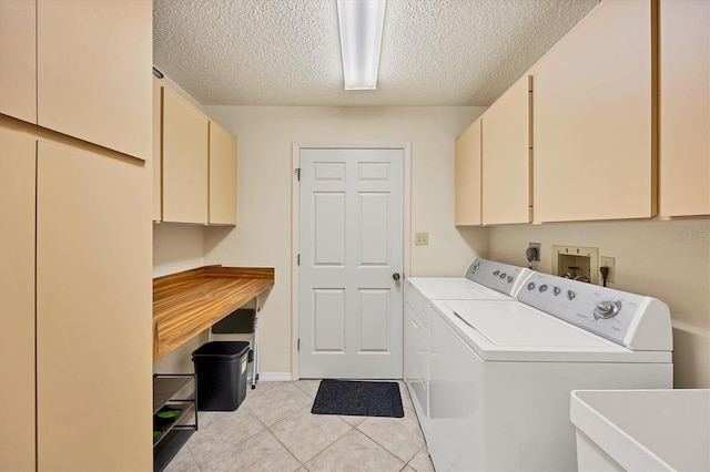 laundry room featuring cabinet space, washing machine and dryer, light tile patterned flooring, a sink, and a textured ceiling