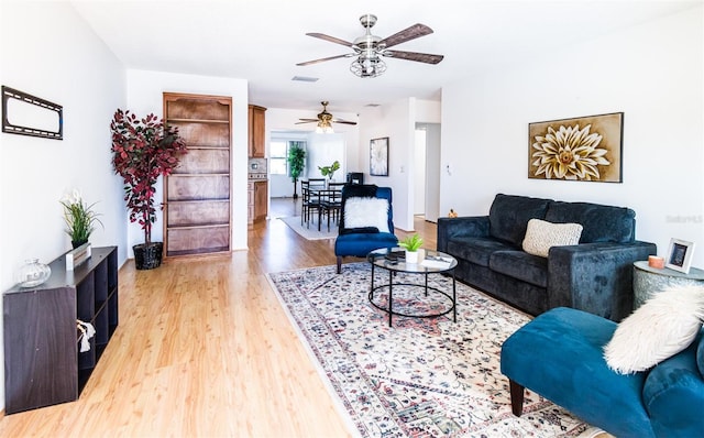 living area with light wood-type flooring, ceiling fan, and visible vents