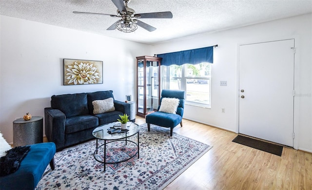 living room with ceiling fan, a textured ceiling, and wood finished floors