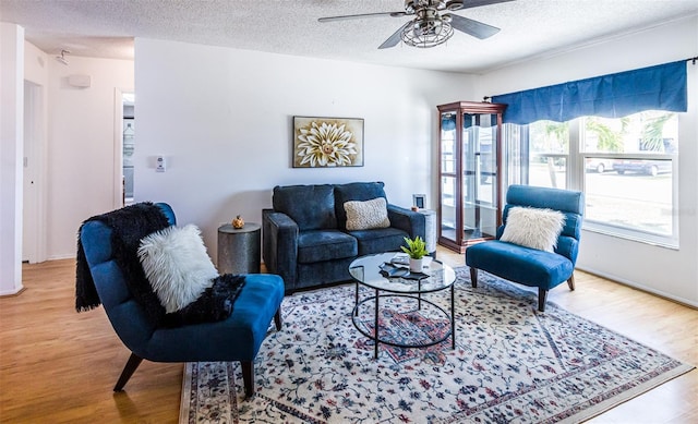 living area with a textured ceiling, ceiling fan, and wood finished floors