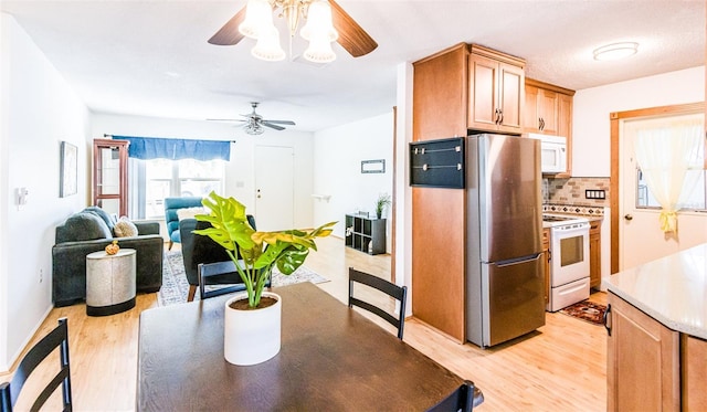 kitchen with light countertops, decorative backsplash, a ceiling fan, light wood-type flooring, and white appliances