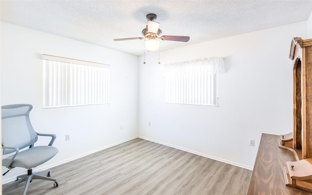 interior space with a textured ceiling, ceiling fan, wood finished floors, and baseboards